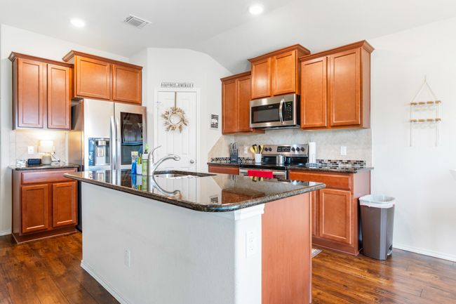 Kitchen with stainless steel appliances, a sink, lofted ceiling, decorative backsplash, and dark wood-style floors | Image 17