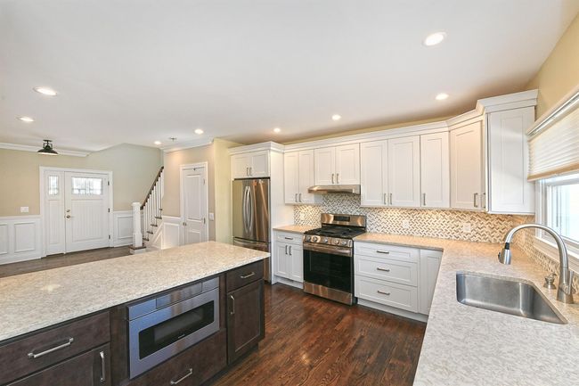 Kitchen with a sink, a wainscoted wall, stainless steel appliances, white cabinets, and under cabinet range hood | Image 16