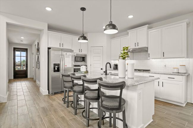 Kitchen with stainless steel appliances, wood tiled floors, white cabinets, decorative backsplash, and recessed lighting | Image 22