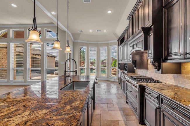The combination of warm cabinetry and polished stone creates a stylish and inviting culinary space. | Image 12