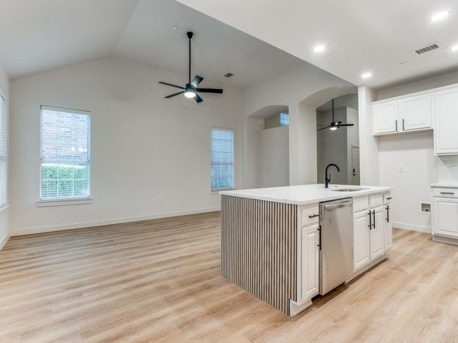 Kitchen featuring stainless steel dishwasher, a ceiling fan, open floor plan, light countertops, and lofted ceiling | Image 10