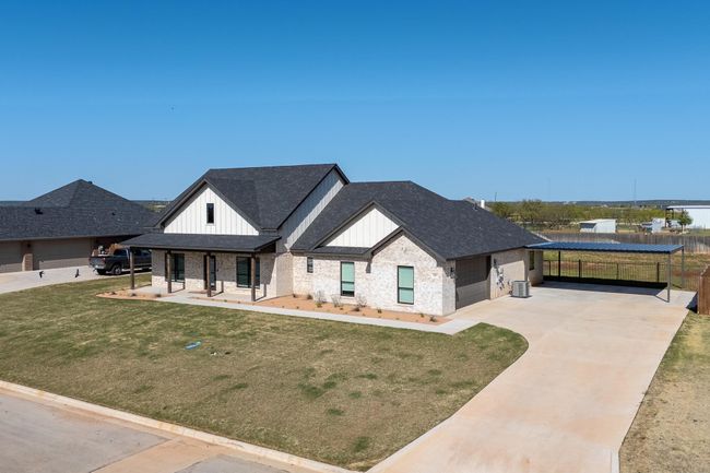 Modern farmhouse style home with a garage, board and batten siding, a front lawn, driveway, and roof with shingles | Image 4