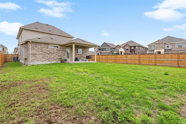 Back of house featuring a patio, brick siding, a residential view, and roof with shingles | Image 37
