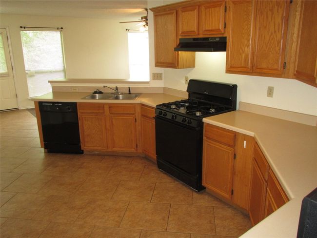 Kitchen featuring black appliances, plenty of natural light, and light countertops | Image 7