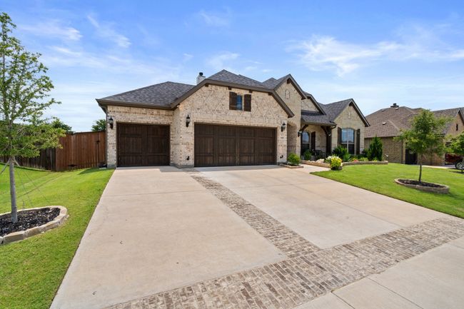 French country home featuring brick siding, a garage, driveway, and roof with shingles | Image 40