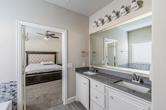Full bathroom featuring ensuite bath, double vanity, a ceiling fan, and wood finished floors | Image 22