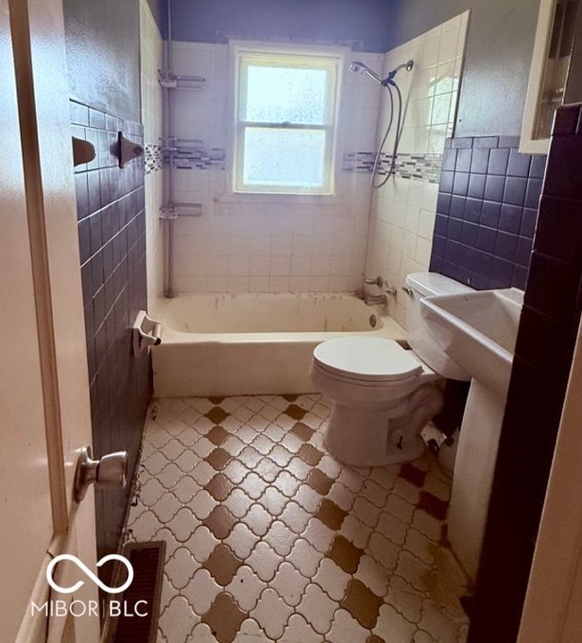 Full bathroom with vintage tile flooring, a window for natural light, and classic tub-shower combo-ready for a refresh or renovation vision. | Image 7