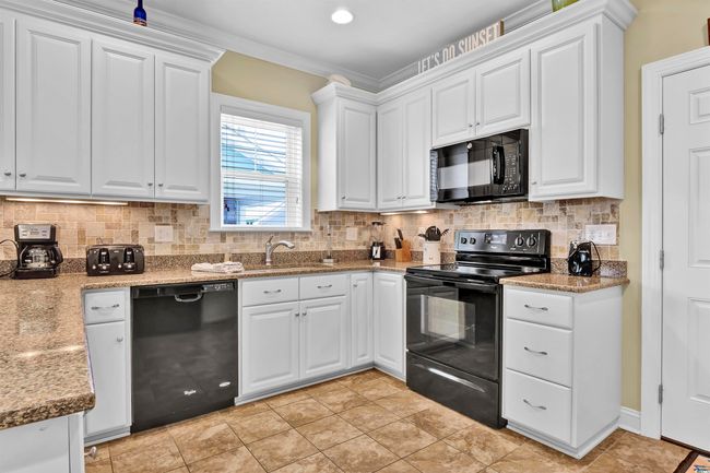 Kitchen featuring black appliances, white cabinetry, and decorative backsplash | Image 10