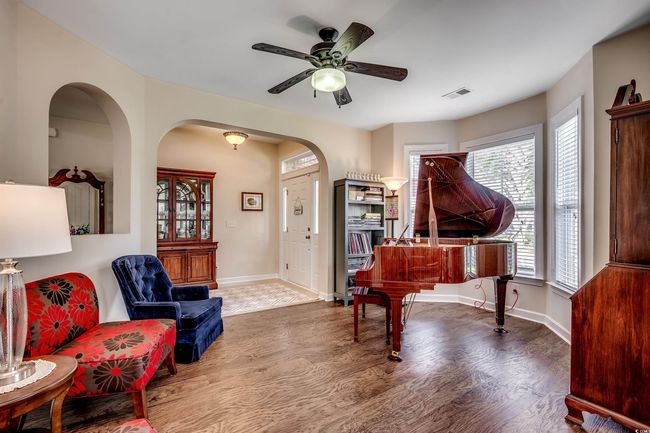 Sitting room with wood finished floors, a ceiling fan, and arched walkways | Image 7