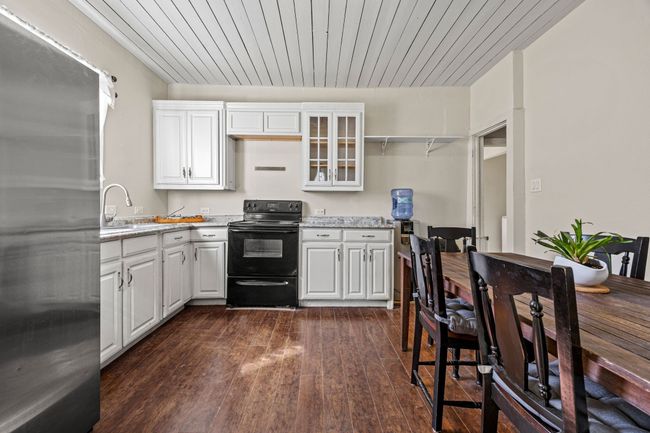 Kitchen with electric range, dark wood-type flooring, white cabinets, a sink, and stainless steel refrigerator | Image 8