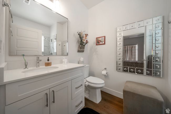 Full bath with wood finished floors, tiled shower, toilet, baseboards, and vanity | Image 9