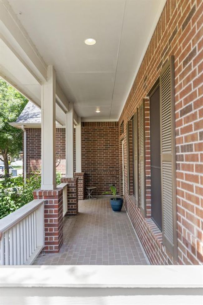 The large front porch spans the width of the home, offering plenty of room for outdoor seating, decor, or a cozy swing. It's a perfect space to unwind while enjoying views of the quiet, tree-lined street outside. | Image 6
