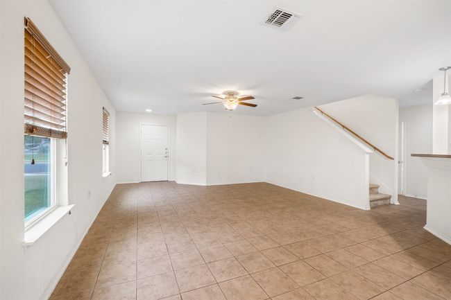 Unfurnished living room with stairs, light tile patterned flooring, ceiling fan, baseboards, and visible vents | Image 15