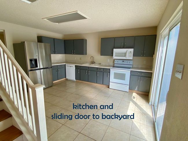 Kitchen featuring blue/gray cabinets, appliances, light countertops, a sink, and a textured ceiling | Image 8