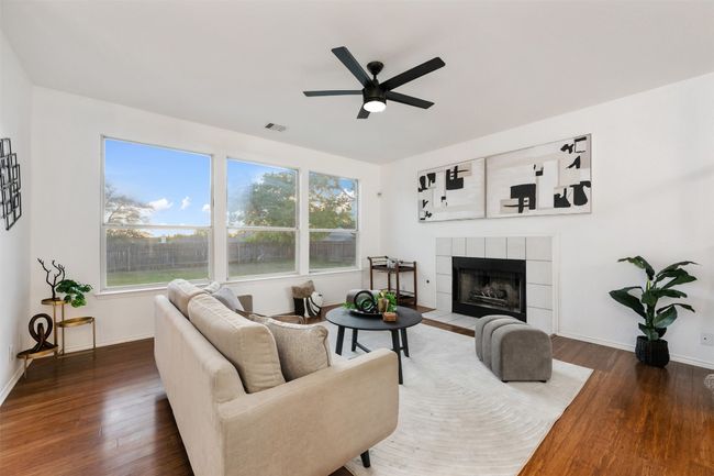 Living room featuring a tiled fireplace, visible vents, ceiling fan, and wood finished floors | Image 5