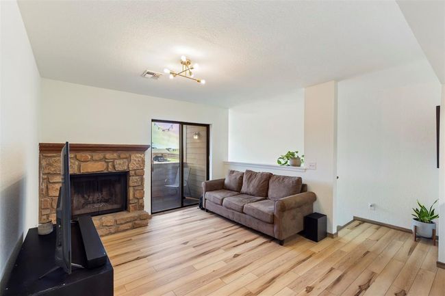 Living area with light wood-style flooring, a fireplace, and a chandelier | Image 9