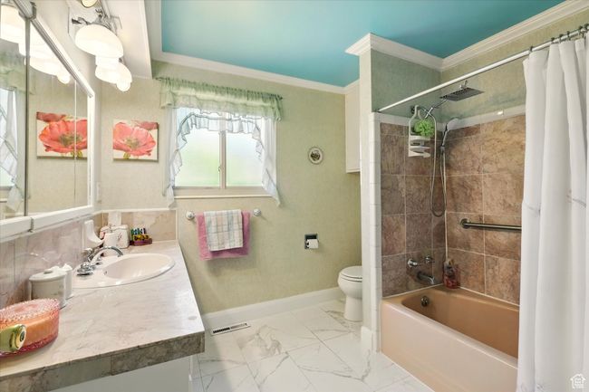 Bathroom with toilet, vanity, ornamental molding, shower / bath combo, and baseboards | Image 22