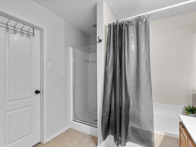 Full bath featuring a shower with curtain, vanity, a tub, and tile patterned flooring | Image 19