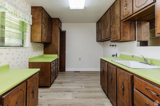 Kitchen with light wood-type flooring, light countertops, a textured ceiling, and wallpapered walls | Image 17
