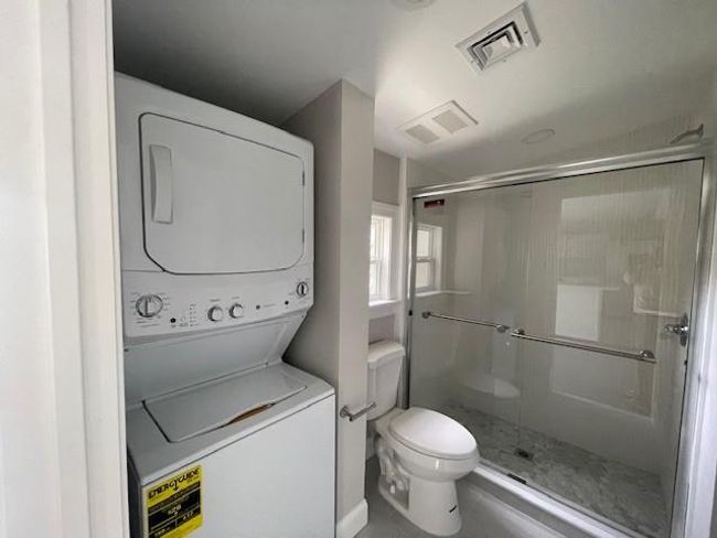 Full bathroom featuring visible vents, stacked washer / dryer, and a stall shower | Image 5