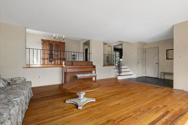 Living room with wood finished floors, a chandelier, and stairs | Image 6