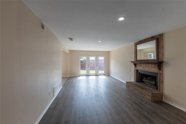 Unfurnished living room featuring baseboards, a fireplace, dark wood-style flooring, recessed lighting, and french doors | Image 31