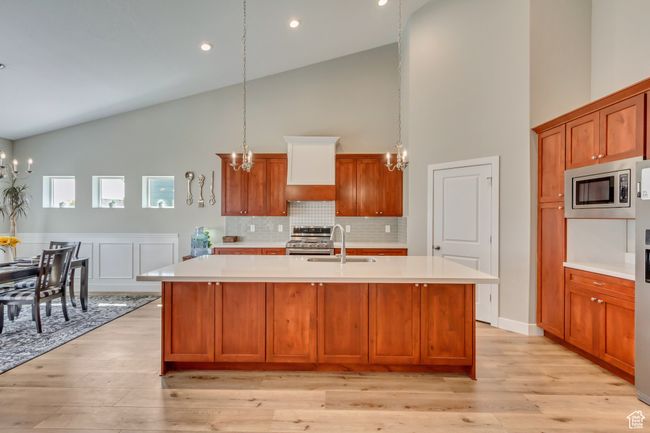 Kitchen featuring stainless steel appliances, light countertops, high vaulted ceiling, and a notable chandelier | Image 11