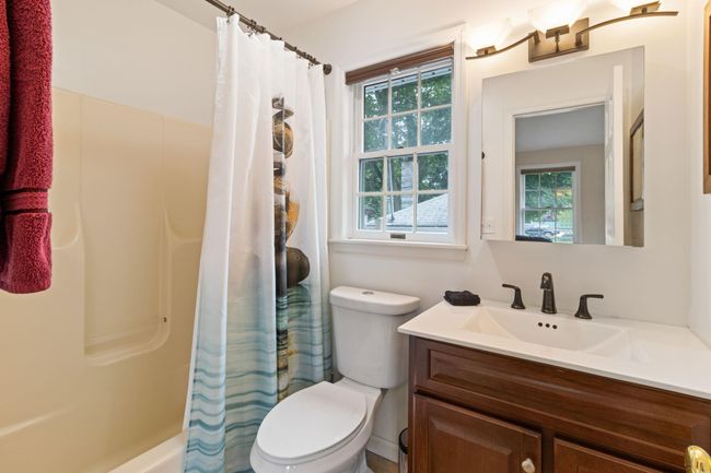 Bathroom featuring shower / bath combination with curtain, vanity, toilet, and plenty of natural light | Image 8