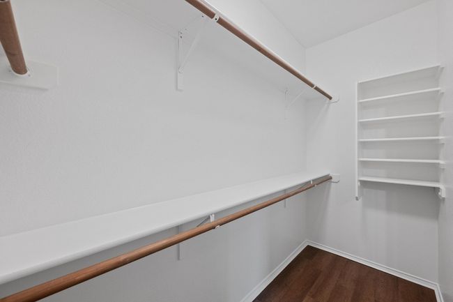 Spacious closet with dark wood-style flooring and attic access | Image 18
