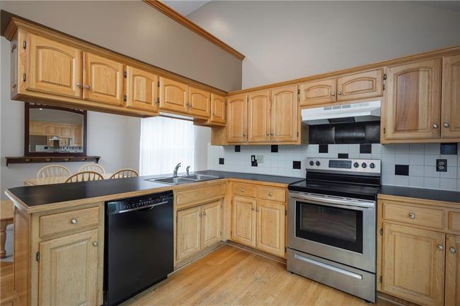 Kitchen with dishwasher, electric range, a sink, under cabinet range hood, and light wood-style floors | Image 13