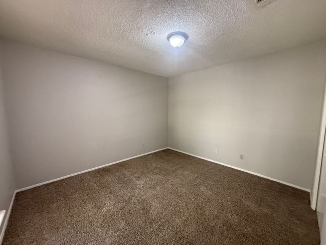 Unfurnished room featuring dark colored carpet and a textured ceiling | Image 16