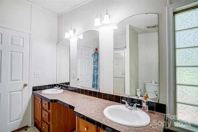 Enjoy a relaxing soak in the tub nestled beneath the frosted window in the primary bathroom. | Image 24