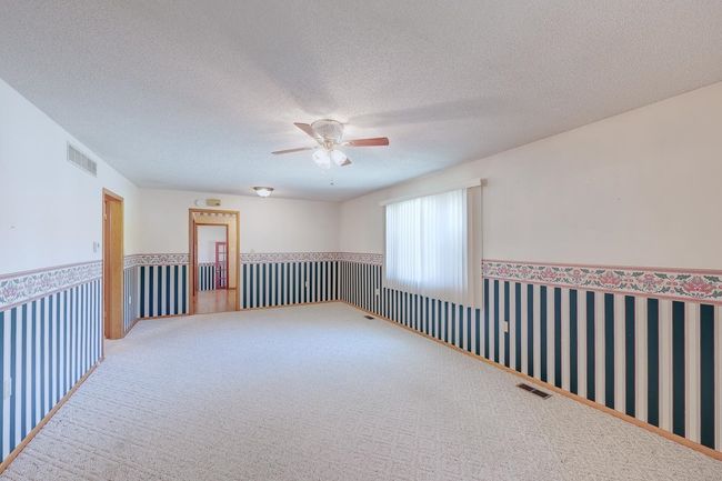 Spare room with a ceiling fan, carpet flooring, a wainscoted wall, and a textured ceiling | Image 17