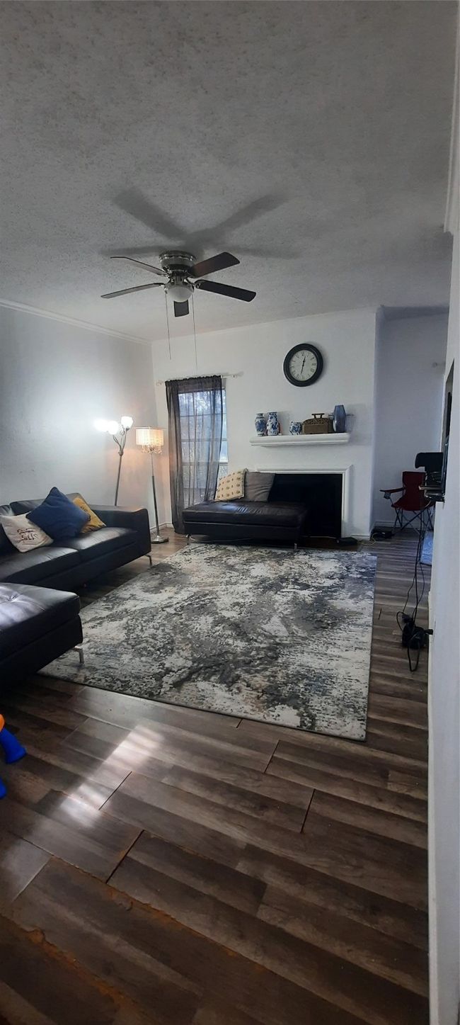 Living area with a textured ceiling, wood finished floors, and a ceiling fan | Image 6