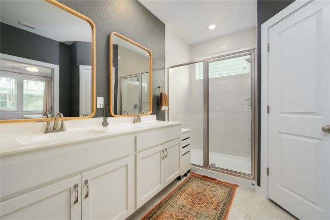 Bathroom featuring a shower stall, double vanity, and plenty of natural light | Image 10