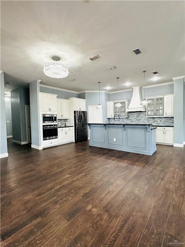 Kitchen featuring stainless steel appliances, dark countertops, premium range hood, ornamental molding, and backsplash | Image 9