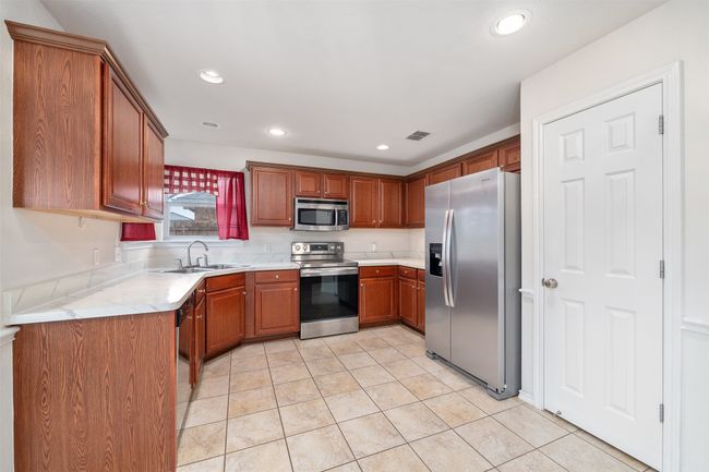 Kitchen featuring light countertops, a sink, appliances with stainless steel finishes, and recessed lighting | Image 6