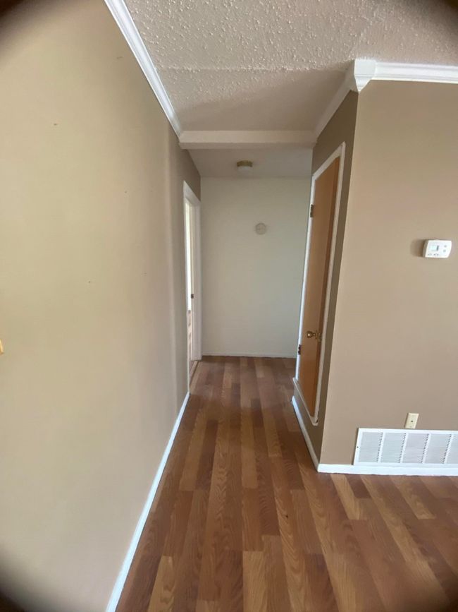 Corridor with crown molding, wood finished floors, and a textured ceiling | Image 11