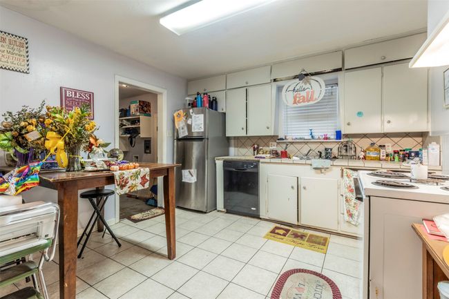 Kitchen with white electric range oven, freestanding refrigerator, light countertops, dishwasher, and tasteful backsplash | Image 10