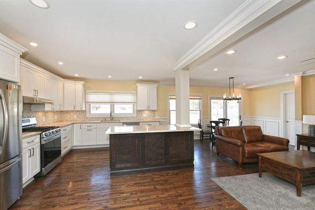 Kitchen with tasteful backsplash, a sink, stainless steel appliances, under cabinet range hood, and a kitchen island | Image 23
