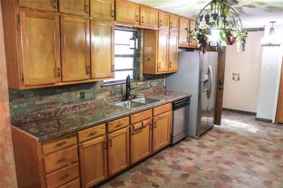 Kitchen featuring hanging light fixtures, stainless steel appliances, vinyl floors, backsplash, and sink | Image 3