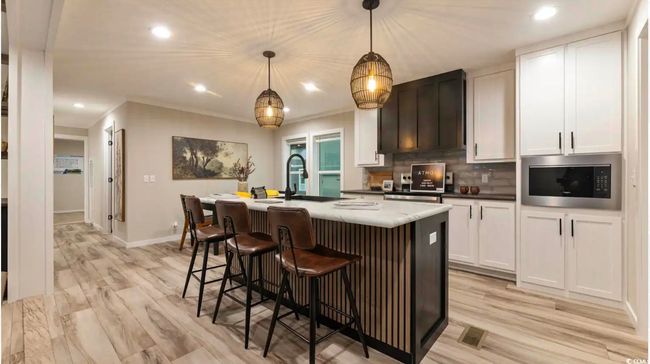 Kitchen featuring stainless steel microwave, a center island with sink, decorative backsplash, recessed lighting, and white cabinetry | Image 8