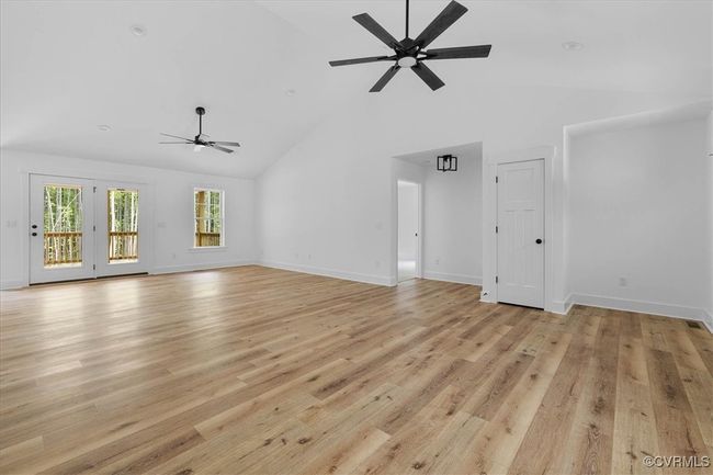 Unfurnished living room featuring light wood finished floors, baseboards, a ceiling fan, and high vaulted ceiling | Image 6