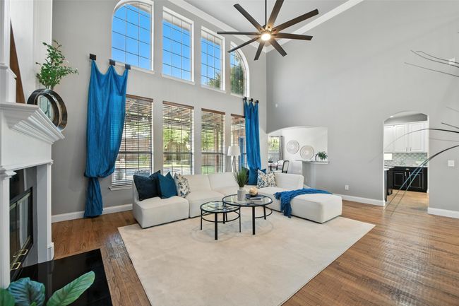 Living area with ceiling fan, wood finished floors, arched walkways, and a glass covered fireplace | Image 6