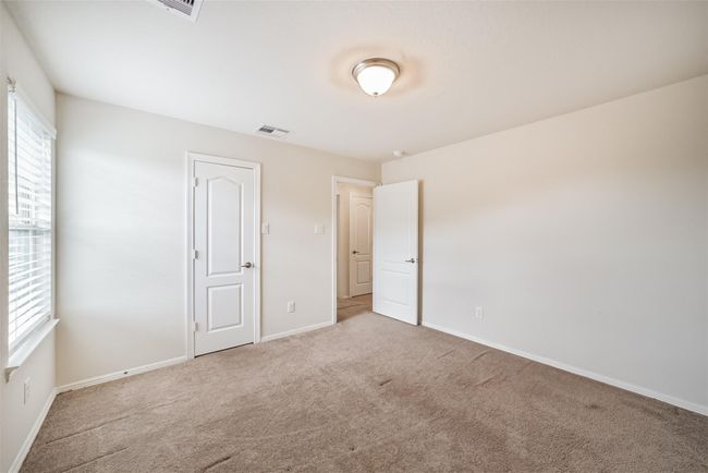 Bright and spacious upstairs bedroom 3 with neutral walls and carpet, featuring a window for natural light and two doors leading to a closet and hallway. | Image 27