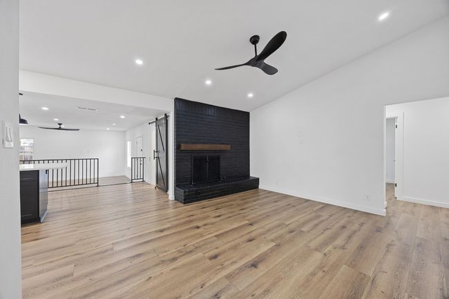 Unfurnished living room featuring ceiling fan, light wood-style floors, lofted ceiling, recessed lighting, and a brick fireplace | Image 21