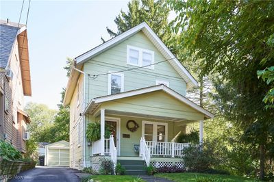 View of front of property featuring covered porch, an outbuilding, and a garage | Image 1