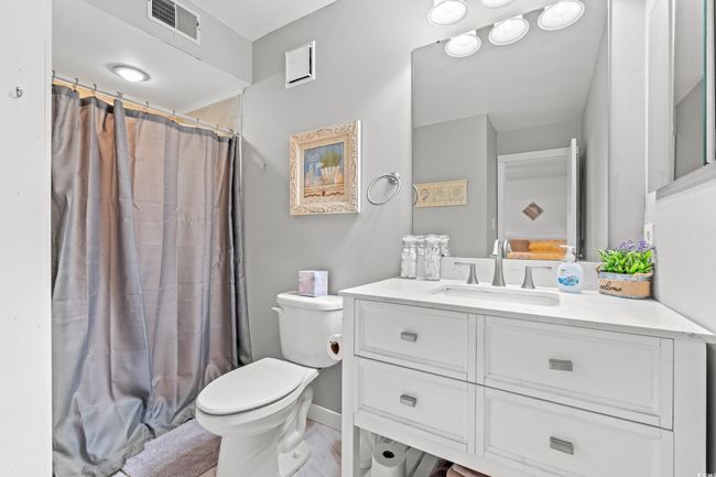 Bathroom with toilet, vanity, a shower with shower curtain, and baseboards | Image 21