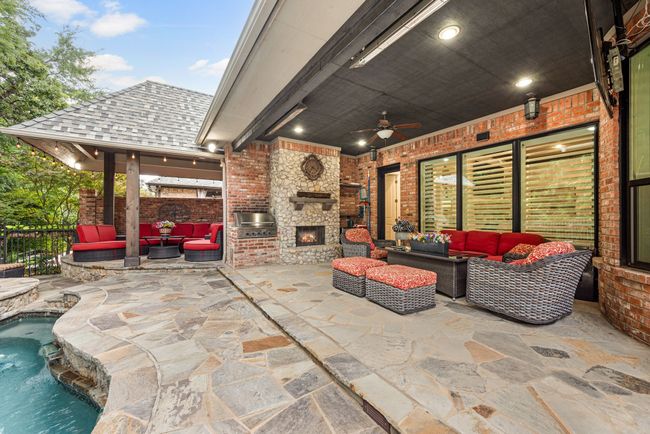 Terraced outdoor living space includes 2 covered patios, a built in grill, gas log fireplace with cedar mantle and adjacent storage shelving. | Image 31