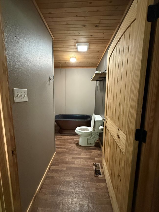 Bathroom with wood ceiling, toilet, a tub, and wood finished floors | Image 23